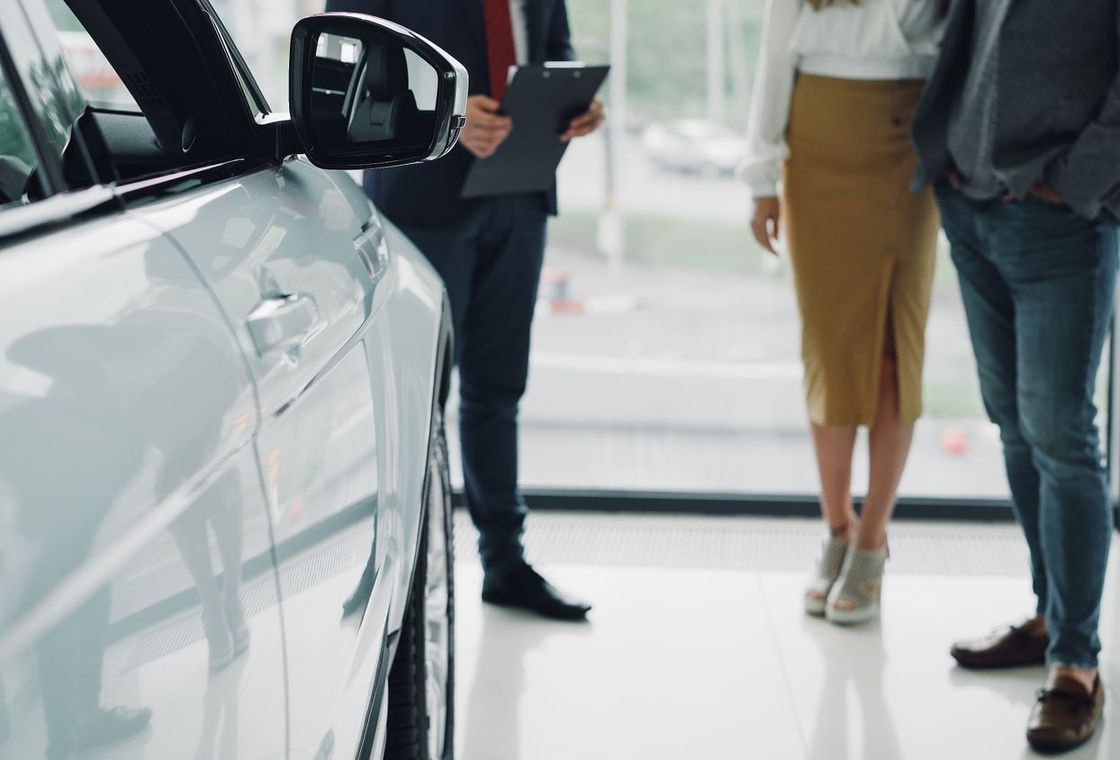 A salesperson discussing finance options with customers in a car dealership showroom
